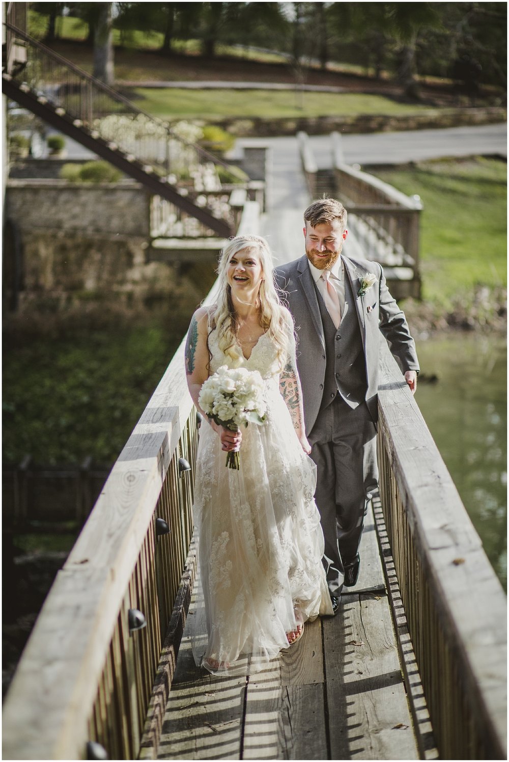 Bride and Groom walk across a bridge to their reception at Evins Mill.