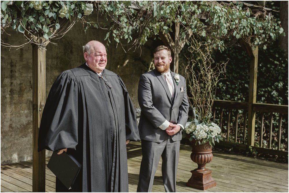 Groom stands next to preacher at Evins Mill Wedding.