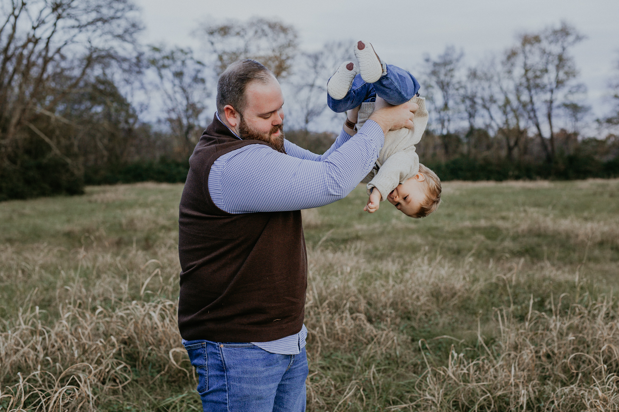 Dad teases his by holding him upside down during spring hill family photos.