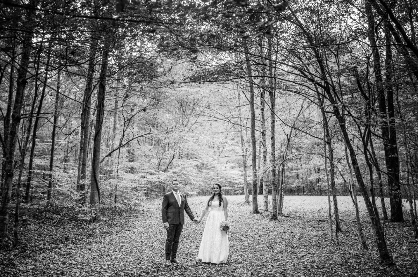 The bride and groom stand amongst a wooded background at Garrett Farm.