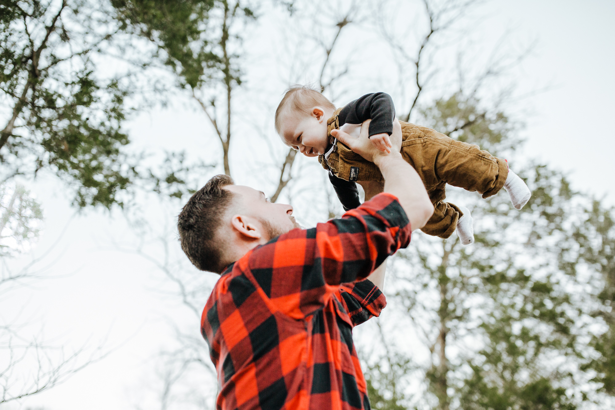 Dad lifts his baby boy high above in the air during their family session in chapel hill.