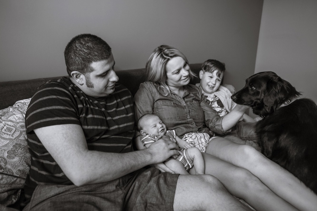 Family talks to dog while holding baby during newborn session in Spring Hill, Tennessee.