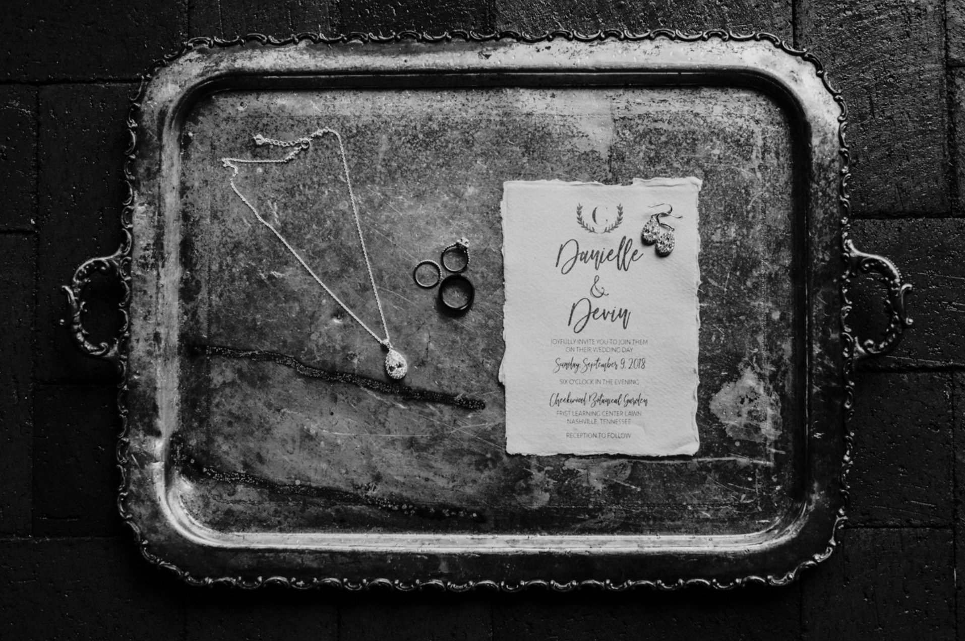 The bride's necklace and wedding ring, invitation and jewelry lay on a decorative tray at their Cheekwood Botanical Wedding.
