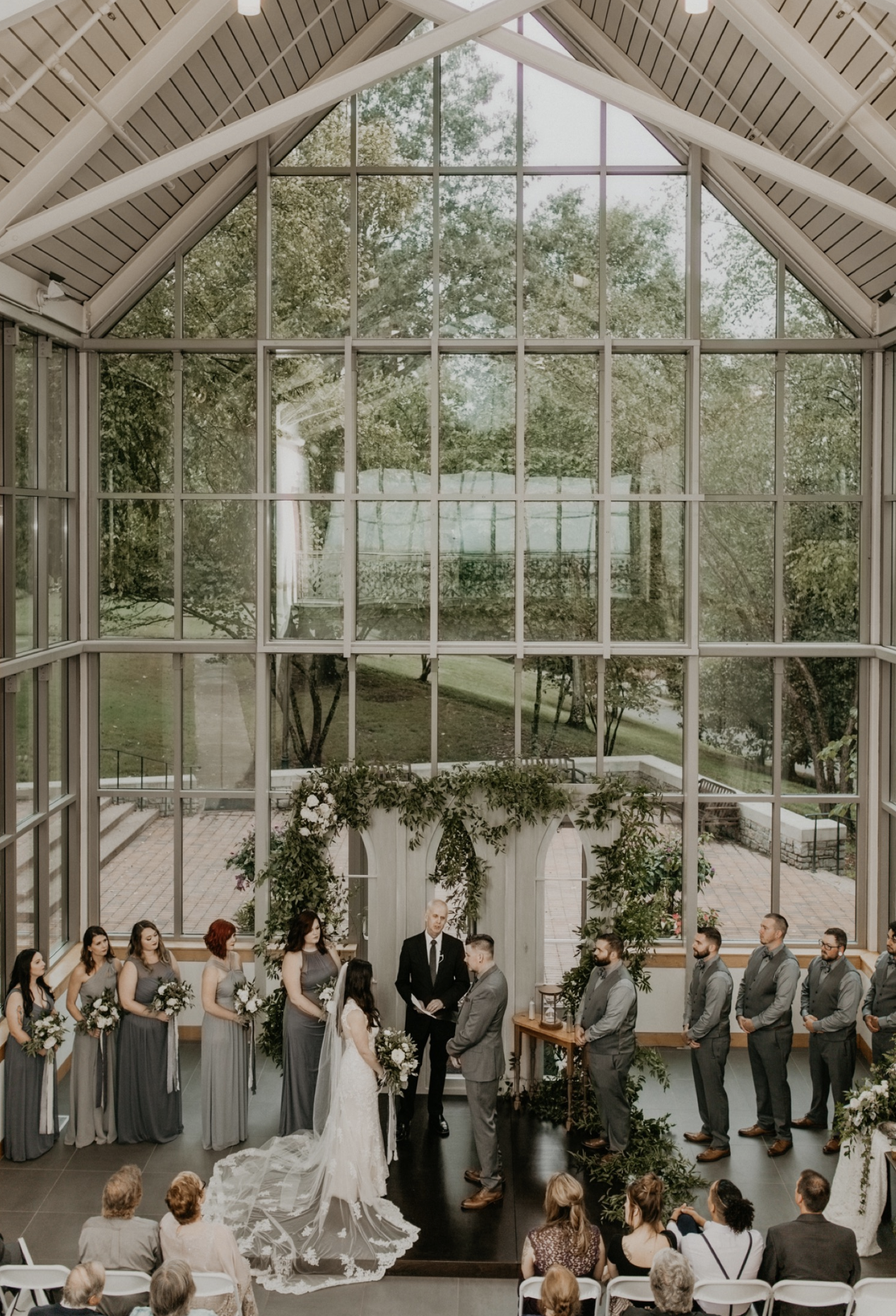 The couple's ceremony inside the Cheekwood Botanical Wedding venue with glass windows.