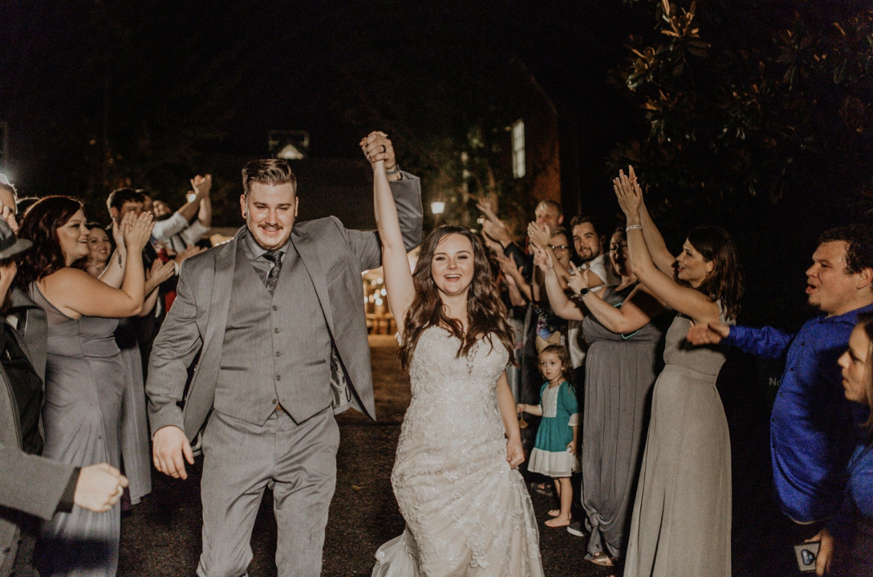 Guests and bridal party cheer the bride and groom on as they leave their wedding at Cheekwood.