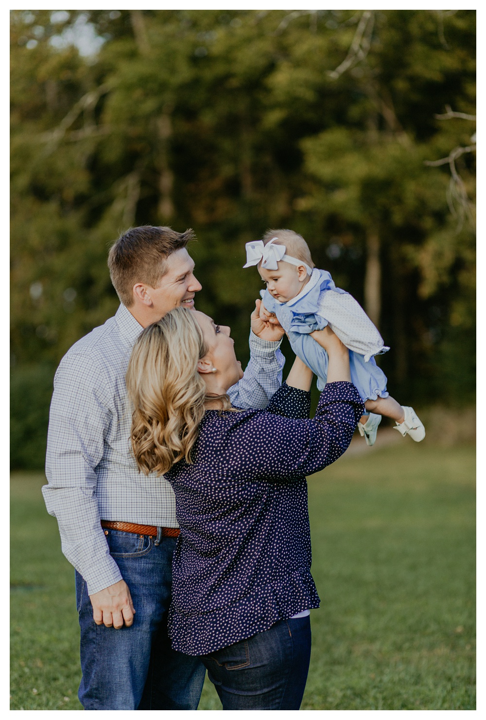 mom holding baby girl while dad makes baby laugh by Nashville family photographer