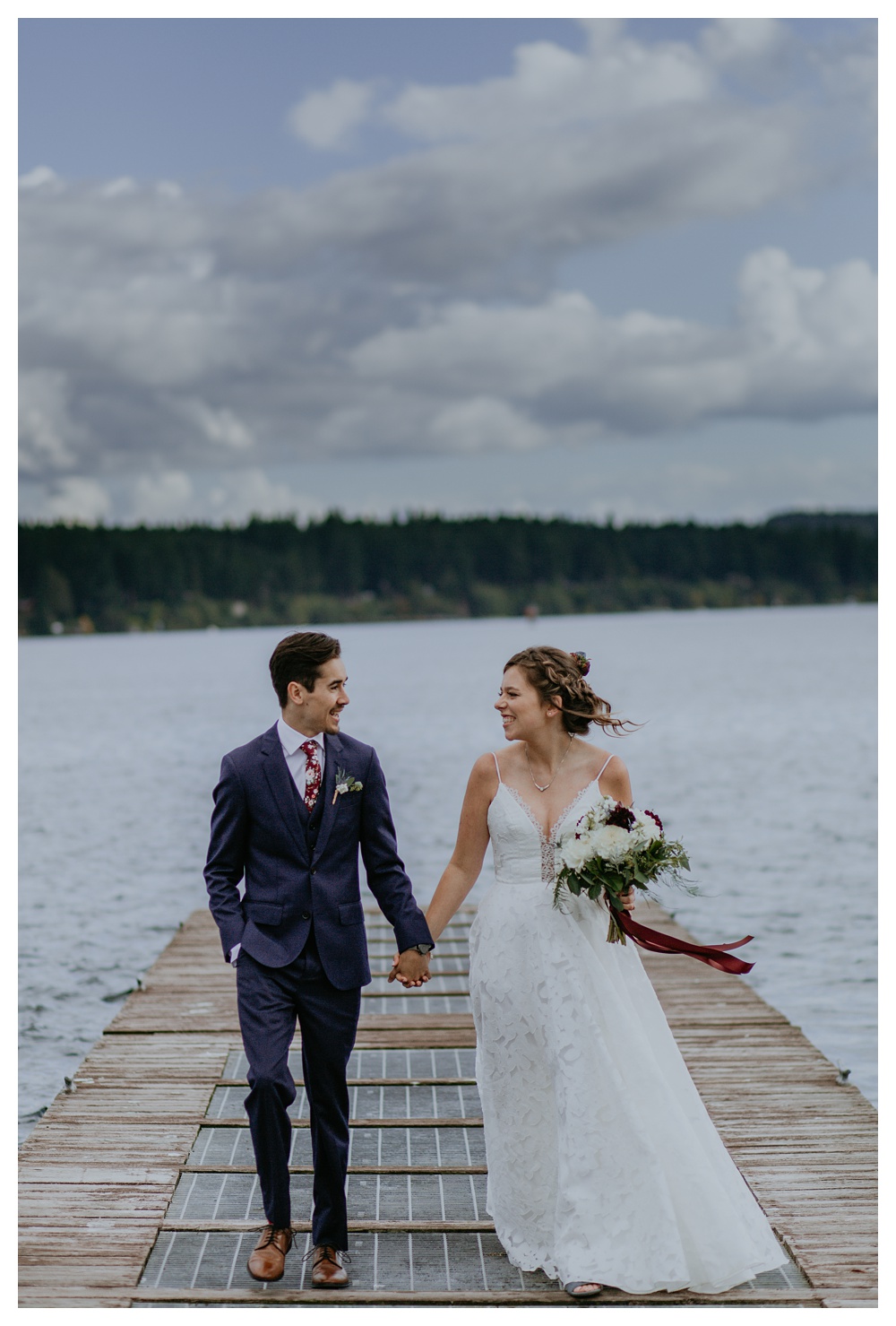 the bride and groom walk on the dock towards the camera at Kiana Lodge.