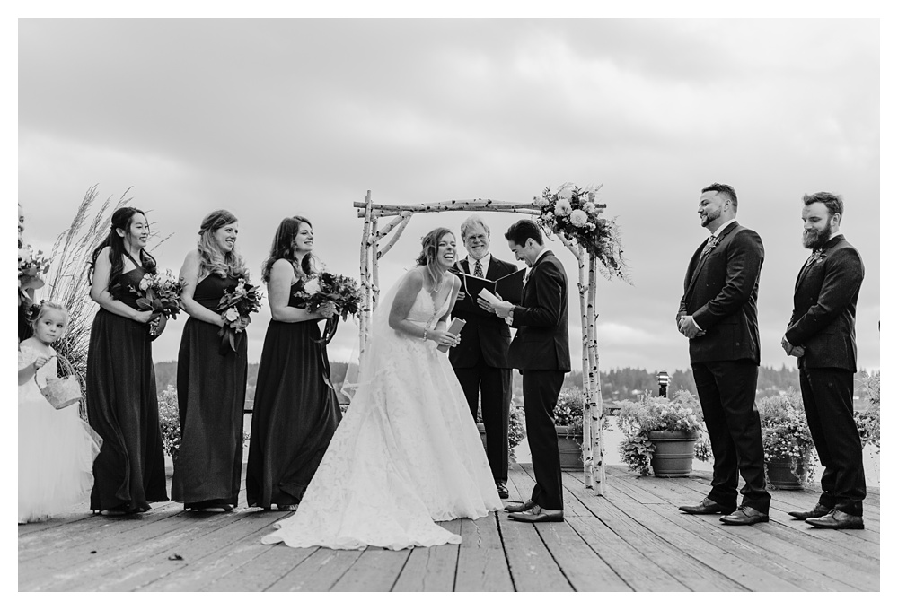 a black and white photo of the bride and groom laughing during their wedding ceremony at Kiana Lodge.
