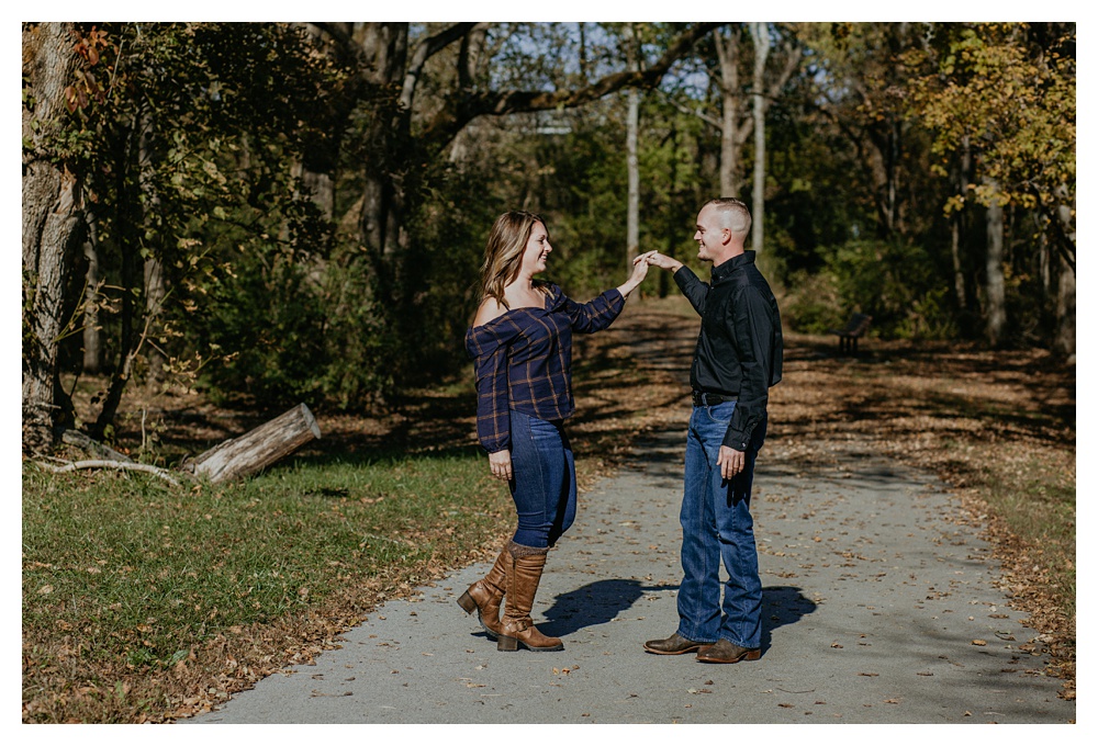 engaged couple dances on walking trail