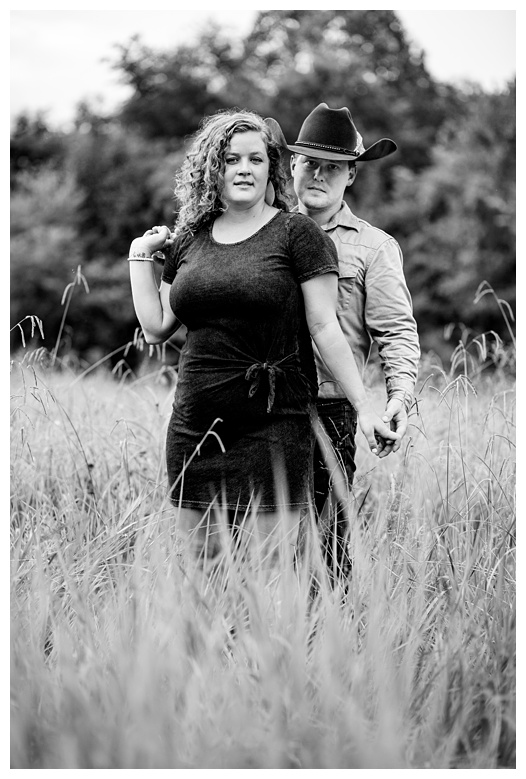 cowboy and cowgirl look seriously at camera, nashville engagement, nashville engagement photographer, Spring Hill Tennessee, outdoor engagement photos, field engagement photos, cowboy hat, cowboy, western engagement photos, Spring Hill engagement photographer, cowboy and cowgirl, summer engagement photos