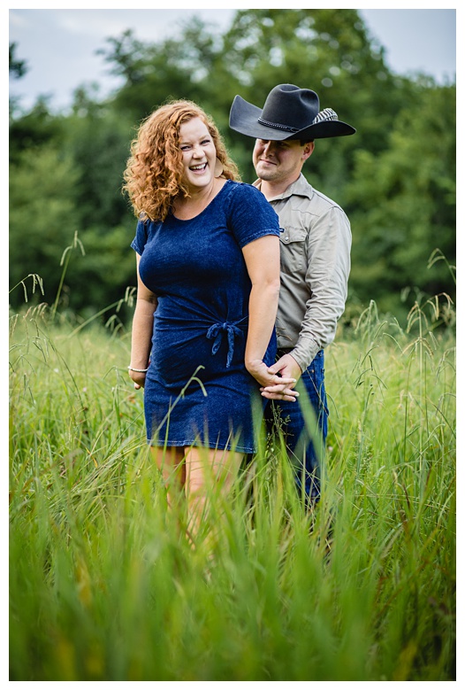 cowboy laughs with cowgirl, nashville engagement, nashville engagement photographer, Spring Hill Tennessee, outdoor engagement photos, field engagement photos, cowboy hat, cowboy, western engagement photos, Spring Hill engagement photographer, cowboy and cowgirl, summer engagement photos
