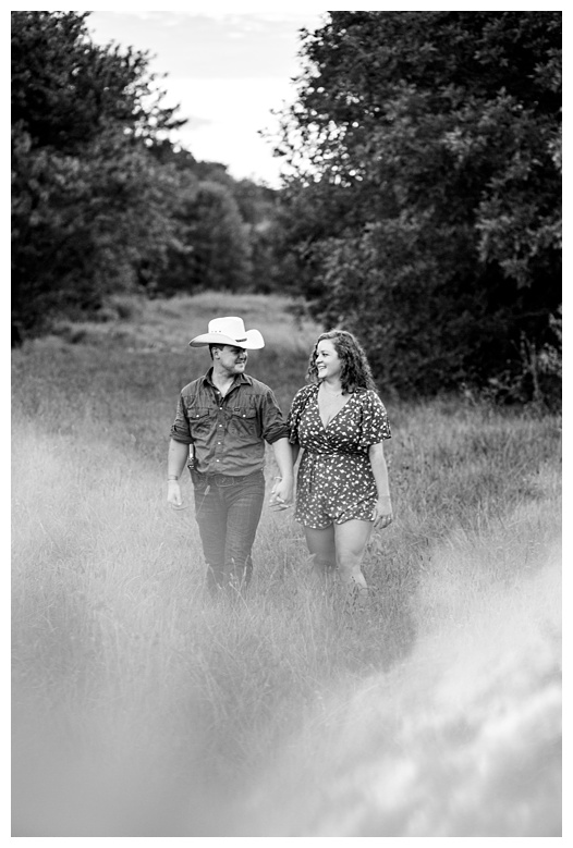 cowboy and cowgirl walk together, nashville engagement, nashville engagement photographer, Spring Hill Tennessee, outdoor engagement photos, field engagement photos, cowboy hat, cowboy, western engagement photos, Spring Hill engagement photographer, cowboy and cowgirl, summer engagement photos