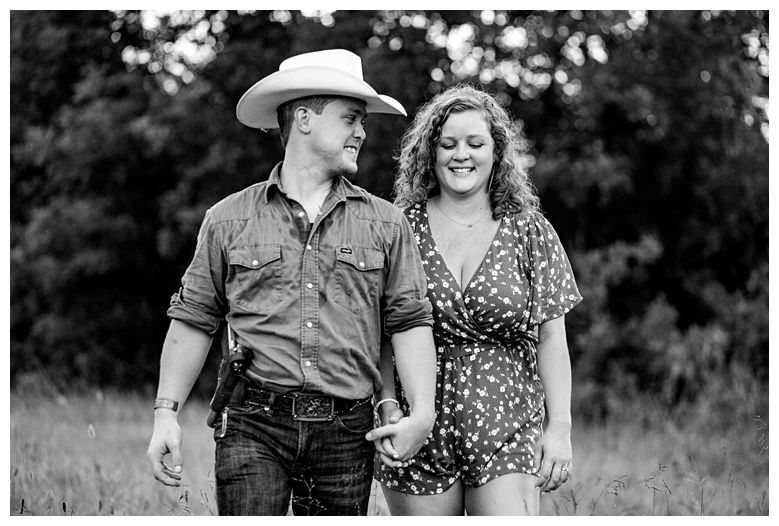 Engaged couple walk holding hands, nashville engagement, nashville engagement photographer, Spring Hill Tennessee, outdoor engagement photos, field engagement photos, cowboy hat, cowboy, western engagement photos, Spring Hill engagement photographer, cowboy and cowgirl, summer engagement photos