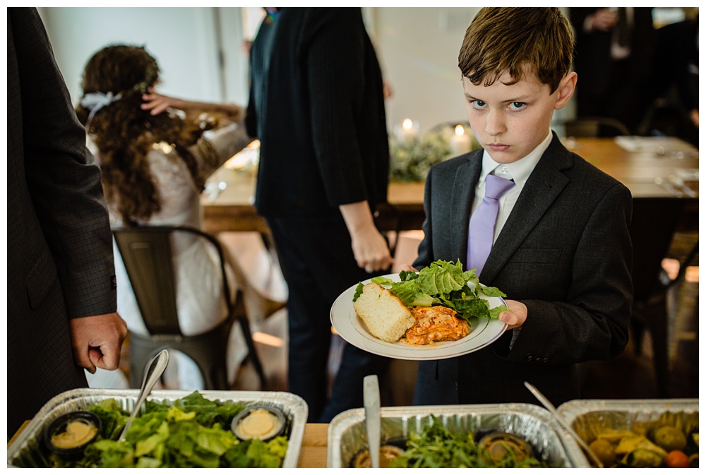 the bride's little brother scowls his face as he gets his food.