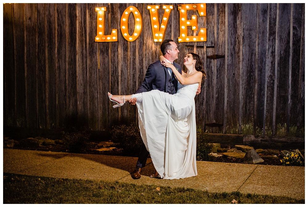 the bride and groom pose in front of the love sign at Drakewood Farm, nashville wedding photographer, nashville wedding, nashville Tennessee wedding, intimate wedding, Drakewood Farm, intimate nashville wedding, intimate outdoor wedding, intimate backyard wedding, intimate elopement, Tennessee elopement
