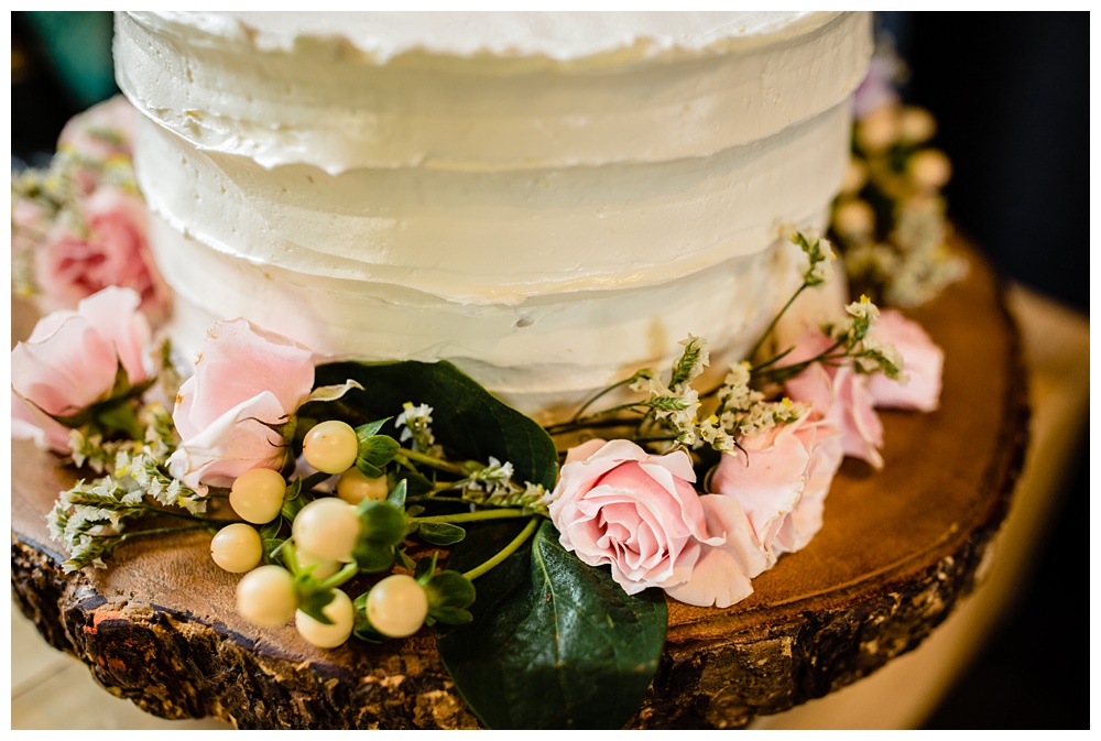 A close up of the celebratory cake adorned with florals around the bottom of it.
