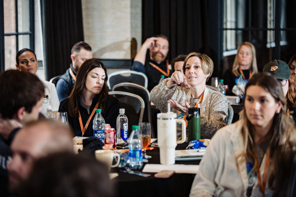 a woman asking a question in a group of a company's corporate attenders.